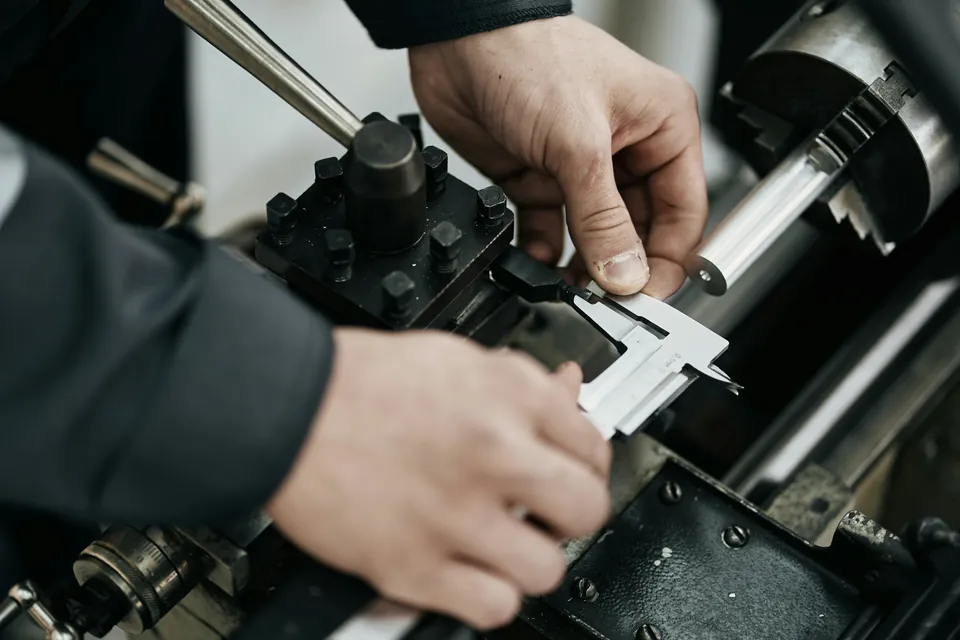 Dłonie technika mierzą suwmiarką element w maszynie