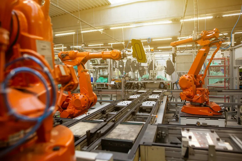 Kilka robotów przemysłowych przy liniach z przyrządami w hali