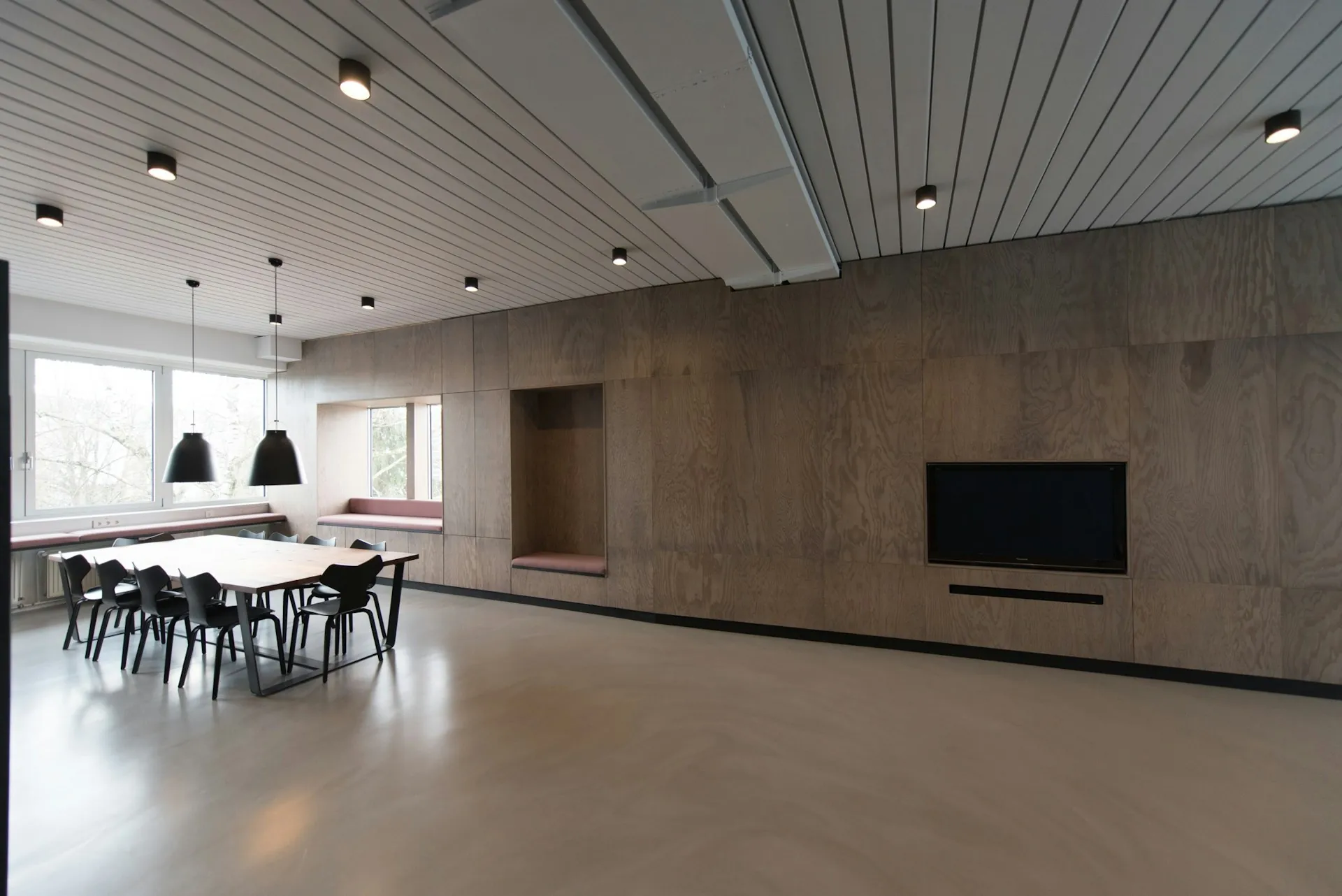Sala spotkań z długim stołem, krzesłami i oknami na zieleń